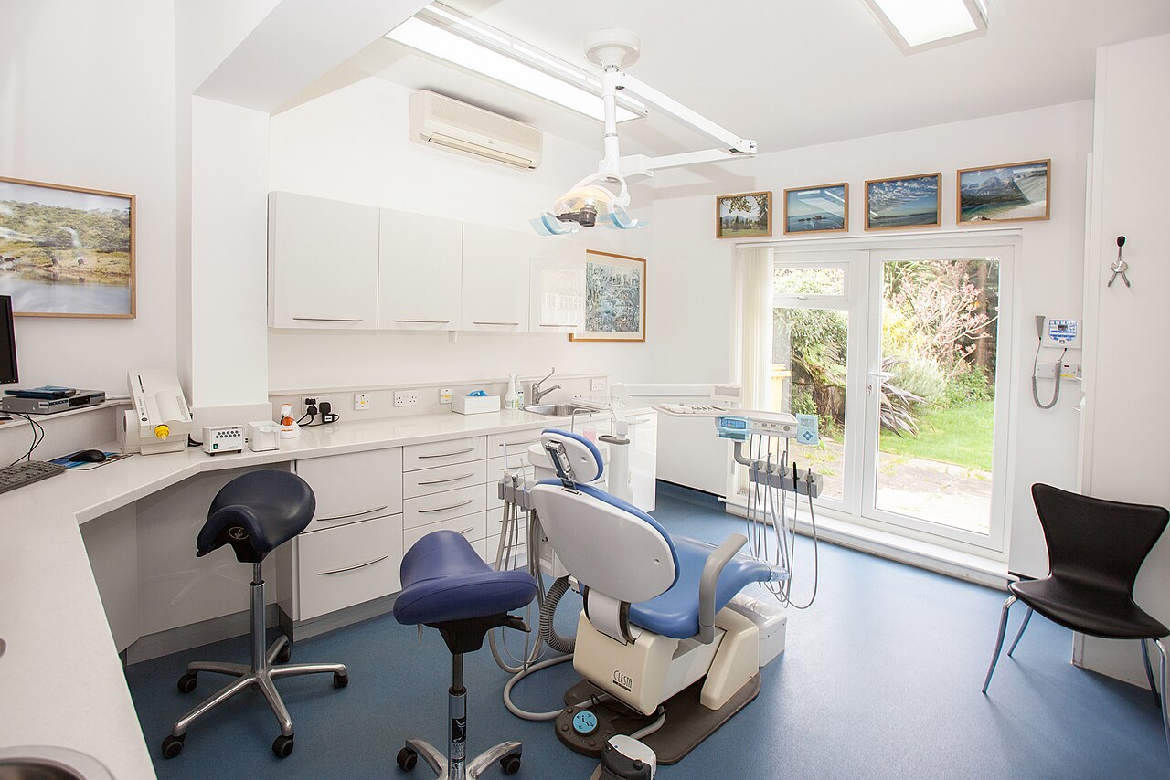 A dental treatment room with a chair, overhead light and instruments