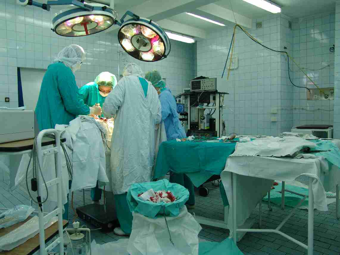 A surgical team working in an operating theatre under overhead lights