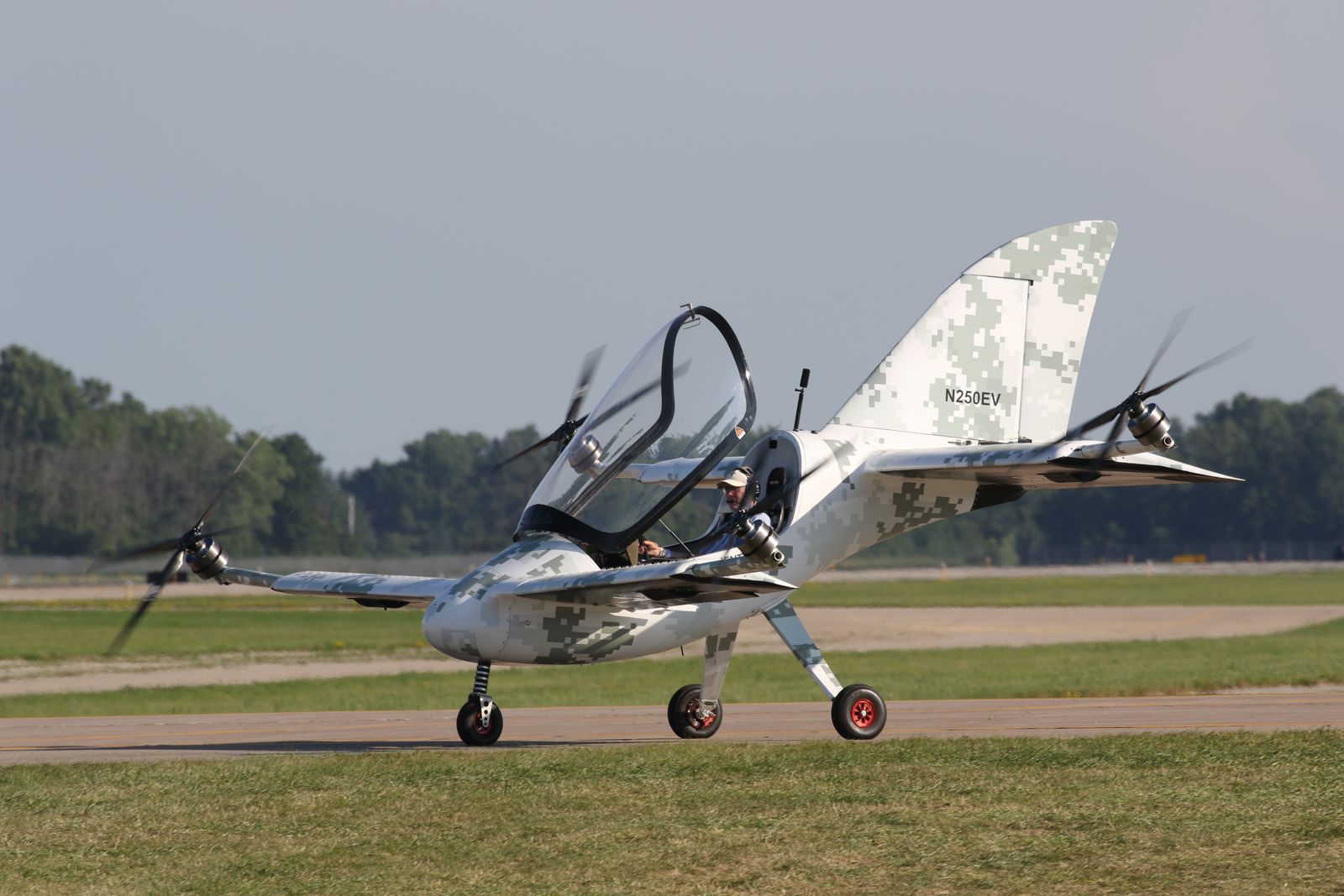A Skyfly-supplied aircraft photograph shows a small multirotor aircraft on a paved surface with its canopy open