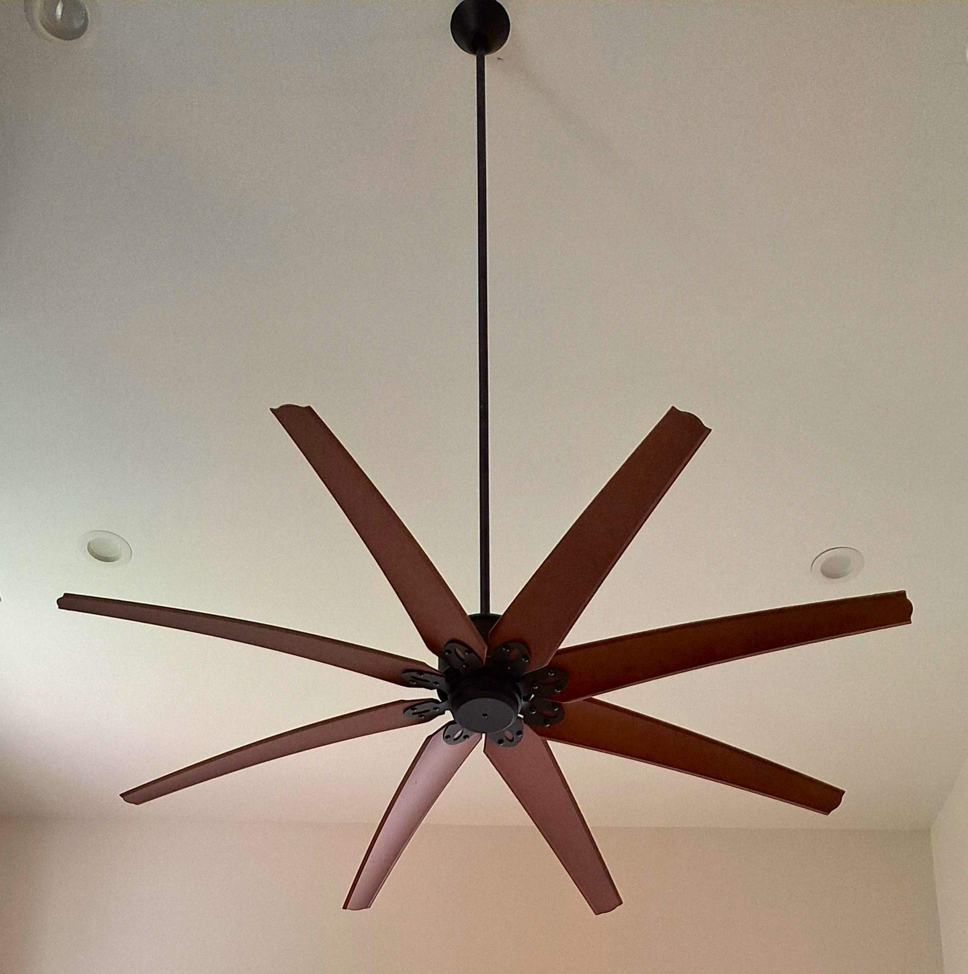 A brown eight-bladed ceiling fan hangs from a pale ceiling.