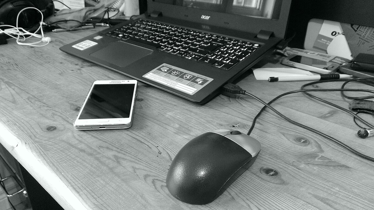 A laptop, computer mouse and smartphone on a desk