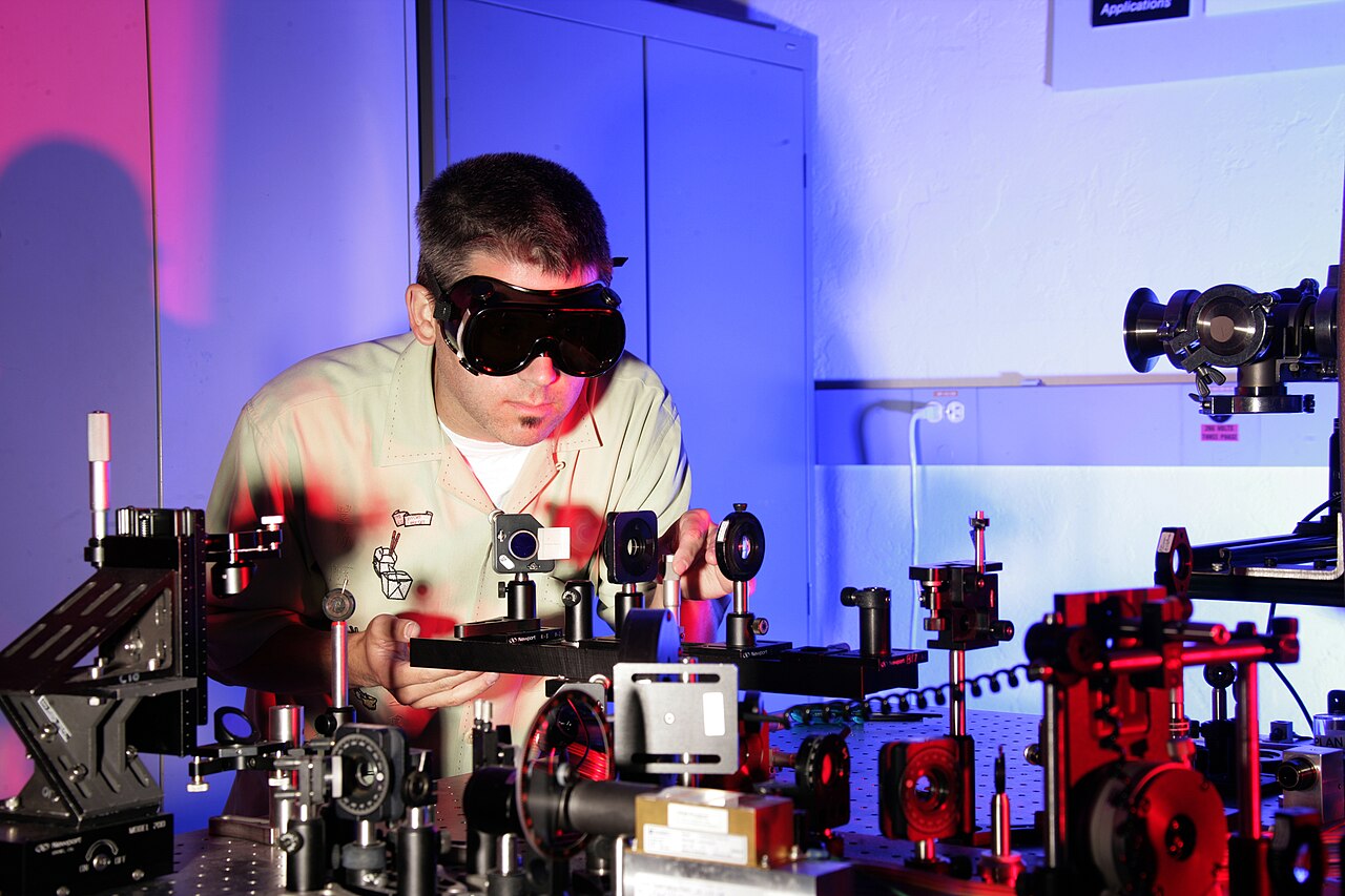 A researcher wearing protective goggles at an optical laboratory bench